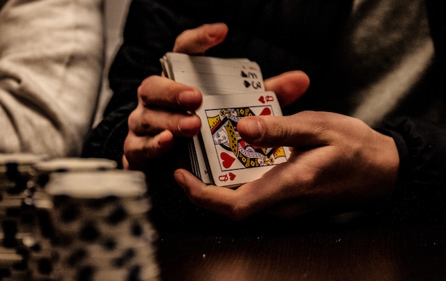 un croupier mélangeant des cartes lors d'une partie de Poker Texas Hold'em et désignant qui parle en premier